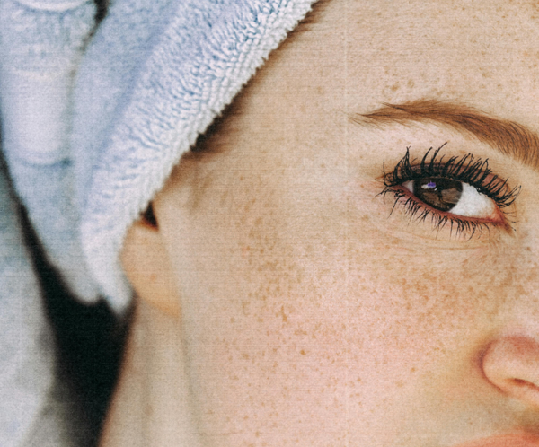 Young woman with brown eyes and freckled face and with towel turban on head looking at camera